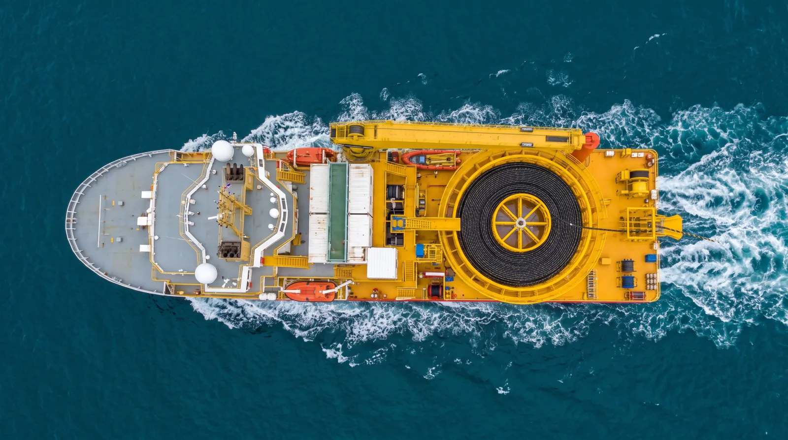 Aerial view of a cable-lay vessel underway with a full cable carousel